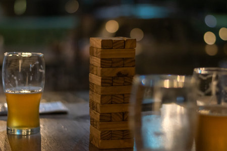 A closeup of glasses of beer with wooden blocks on the tableの写真素材