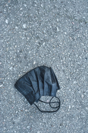 A vertical closeup shot of an abandoned black protective mask on the street