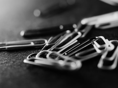 A grayscale selective focus shot of a scattered pile of paperclips in the officeの写真素材