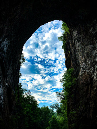 A breathtaking vertical shot of a bright cloudy sky through a cave in the Rock City Gardens, USA