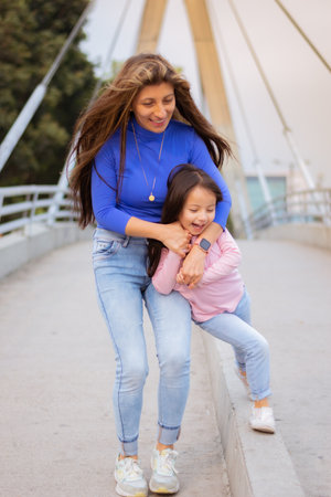 An adorable Latin mother and daughter walking through the city and havingの写真素材