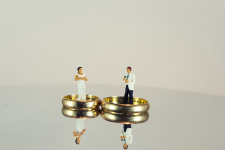 The wedding rings and minifigures of bride and groom reflecting on the surface- concept of marriageの写真素材