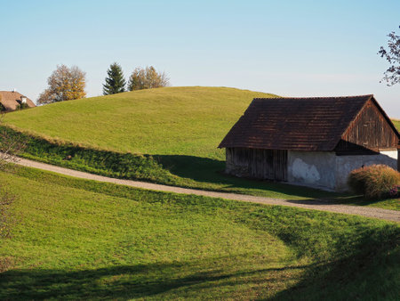 A selective focus shot of a rural house and trees on hills on a sunny dayの写真素材