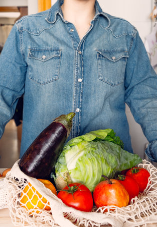 A vertical shot of a woman picking up sustainably made shopping with cardboard and cloth bagの写真素材