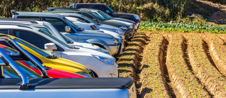 A closeup shot of parked cars near a plowed land