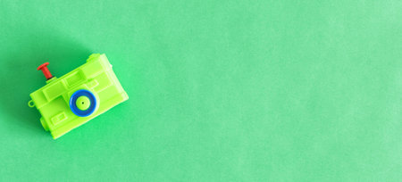 An isolated toy camera, green color, on a green background.