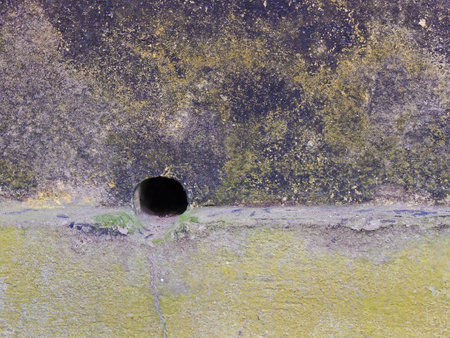 A shot of outside stucco wall covered in yellow and purple colors with a little hole in the wall.の写真素材