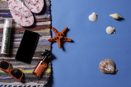 A top view of sunglasses, sandals and sea shells on a blue backgroundの写真素材