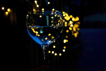 A closeup shot of a wine glass with colorful lights in the backgroundの写真素材
