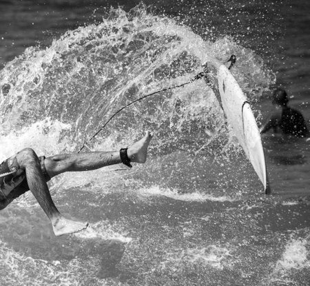 A grayscale shot of a person surfing on the wavesの写真素材