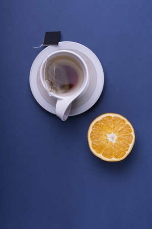 A vertical shot of white cup tea with sliced orange on dark blue backgroundの写真素材