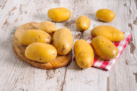 A closeup of fresh raw potatoes on a wooden boardの写真素材
