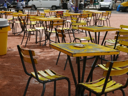 Unoccupied yellow tables and chairs outside on a bar terraceの写真素材