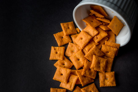 The poured out crackers from the bowl in black backgroundの写真素材