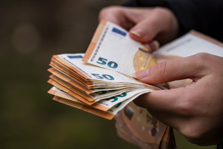 A selective focus shot of a female hand counti euro banknotesの写真素材