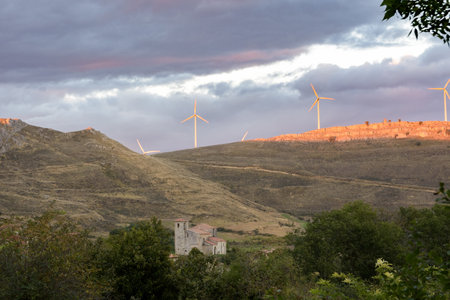 A view of the Monasterio de Rodilla Church with mountains and turbines in the background in Burgos, Spainの写真素材