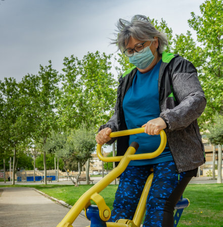 obese senior woman doing sports in the park slimming diet with face maskの写真素材