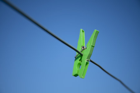 A low angle shot of a green hanging clip on a black cableの写真素材