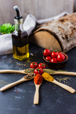 The wooden spoons with spices, paprika, basilic, pepper, thyme with cherry tomatoesの写真素材