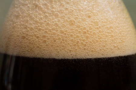 A glass of dark beer with foamの写真素材