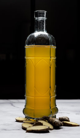 A vertical shot of cut ginger and a bottle of lemon and ginger kombucha: probiotic fermented teaの写真素材