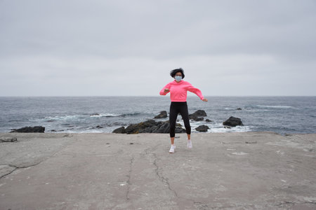 A Chilean woman with a mask exercising in front of the sea - New normality, sport during pandemicの写真素材