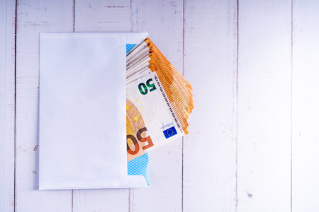 A closeup shot of 50 euro bills in an envelope on a wooden surface with a copy spaceの写真素材