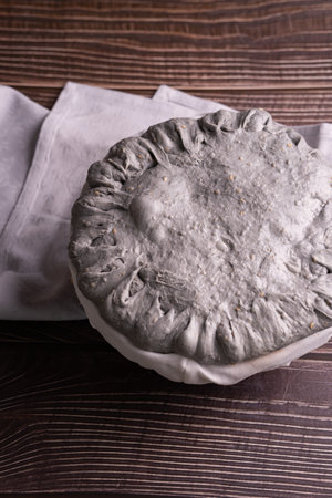A closeup view of a person holding a sourdough for black bread with sesame seedsの写真素材
