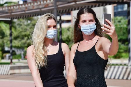 A shallow focus shot of friends in medical masks taking a selfieの写真素材