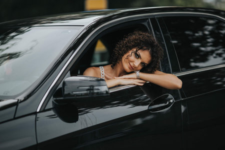 A young sexy Bosnian girl sitting in a black car and looking out of the windowの写真素材