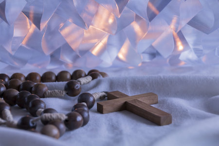 A wooden cross with candle lights in the backgroundの写真素材
