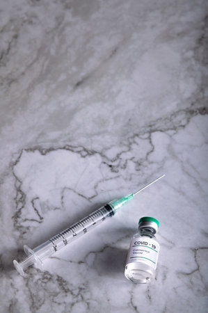 A top view of a syringe with COVID-19 vaccine on cracked white backgroundの写真素材