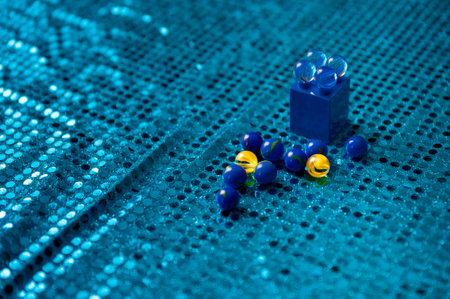 A closeup shot of marbles on blue sequin fabricの写真素材