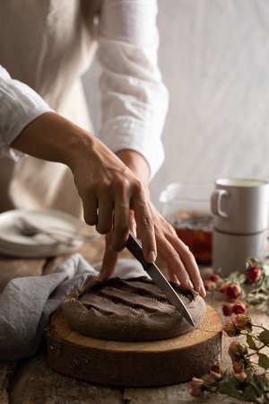 Photo of a gluten free jam Tart in a wooden table next to  bunch of roses, cutting jam tart on trunk chopping boardの写真素材