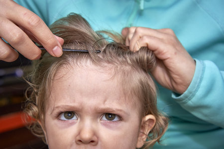 A cute view of the mother doing the hair of the kid, trying to separate hair with the comb