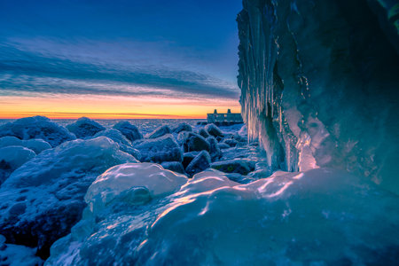 A view of frozen water on stones created by wind and waves on a shore on a wonderful sunset