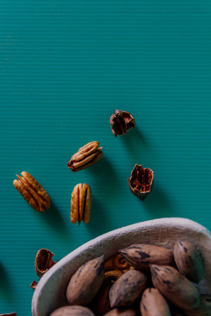 A vertical closeup shot of whole and shelled pecans on a green surfaceの写真素材