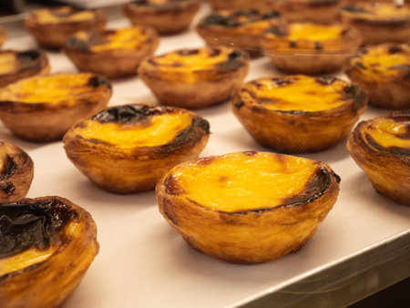 A closeup shot of rows of freshly baked pastel de nata on a pink smooth surface