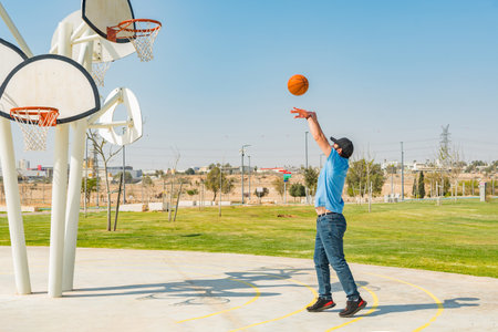 Side view of a young boy playing basketball in a sports park.