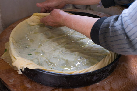 Greek Spinach Pie With Feta Cheese ,preparation of traditional village spinach pie by an elderly woman, kneading and making a pie, village of Greeceの写真素材