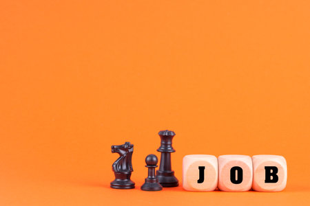 The chess pieces and word JOB formed with wooden blocks in the orange background