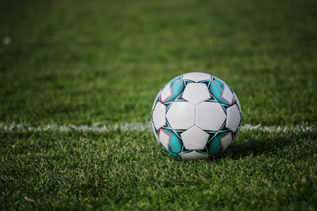 A shallow focus of a football ball on empty field with fresh green grass