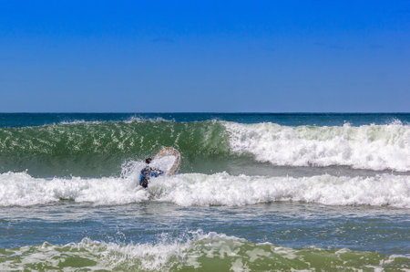 A surfer swimming forward to the waves of the oceanの写真素材