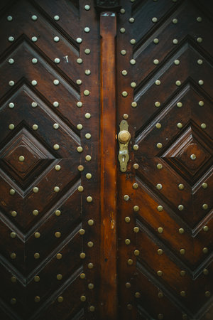 A vertical shot of an old brown door with iron rivets - for backgrounds and texturesの写真素材