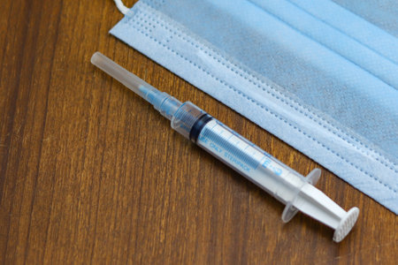 A syringe and a face mask on a wooden backgroundの写真素材