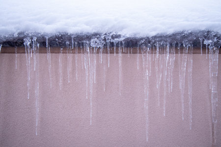 A closeup shot of icicles on the edge of a roof during wintの写真素材