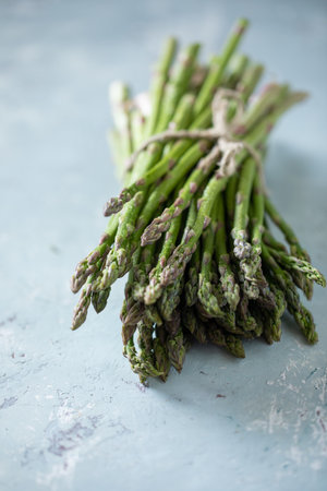 A closeup shot of fresh green asparagus with a rope tied on a blurred backgroundの写真素材