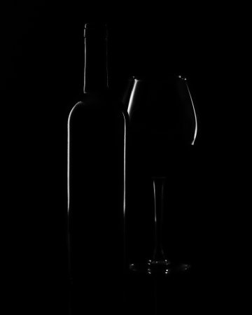 Bottle and wine glass on a black background. Minimalist concept.の写真素材