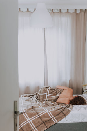 A vertical shot of a female sleeping in bed on a sunny morningの写真素材