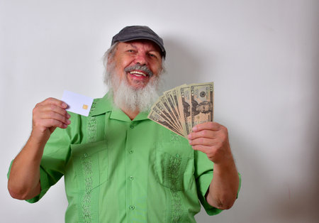 Old American male with green shirt holding us dollars and a credit card